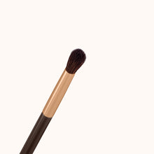 Load image into Gallery viewer, A precise eye crease makeup brush with a rose gold ferrule with a dark brown lacquered handle, made using handcrafted synthetic dark brown bristles mixed with a few strands of white bristles.
