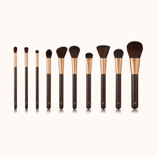 Load image into Gallery viewer, An array of the entire makeup brush collection. Makeup brushes with a dark brown lacquered handle and a rose gold ferrule, made by mixing handmade synthetic dark brown bristles with a few strands of white bristles.
