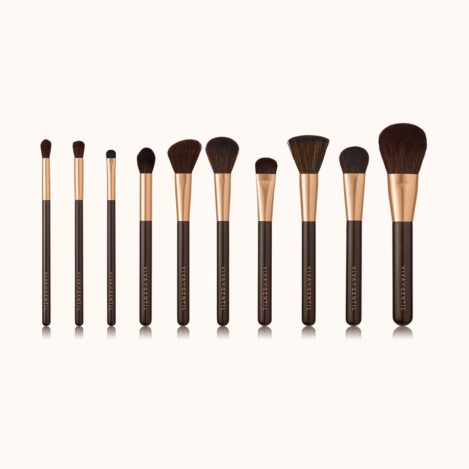 An array of the entire makeup brush collection. Makeup brushes with a dark brown lacquered handle and a rose gold ferrule, made by mixing handmade synthetic dark brown bristles with a few strands of white bristles.