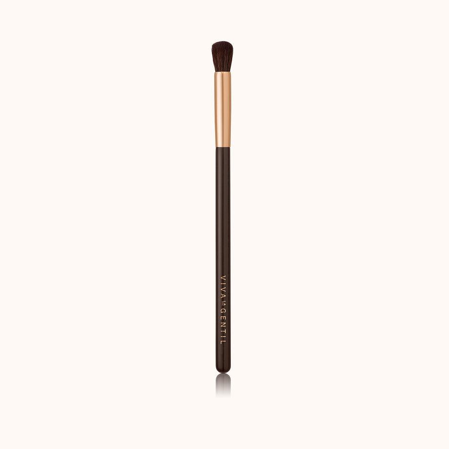 Small, detailed dome-shaped makeup brush with a dark brown lacquered handle and a rose gold ferrule, made by mixing handmade synthetic dark brown bristles with a few strands of white bristles.