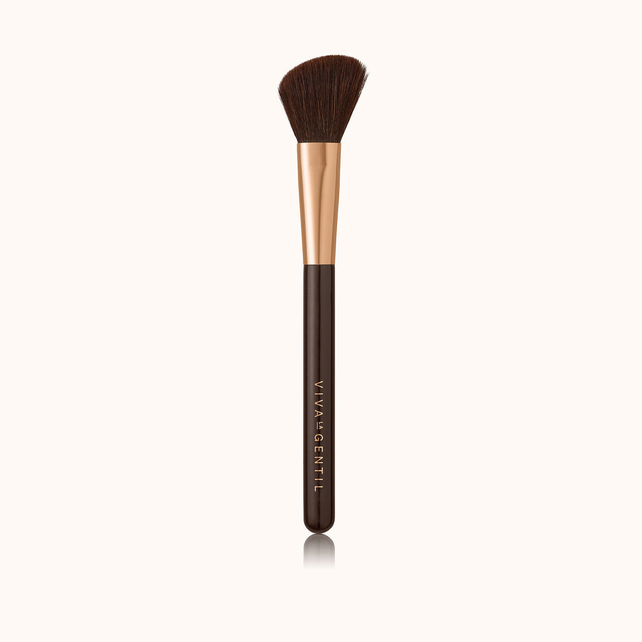 A fluffy angled face makeup brush with a dark brown lacquered handle and a rose gold ferrule, made by mixing handmade synthetic dark brown bristles with a few strands of white bristles.