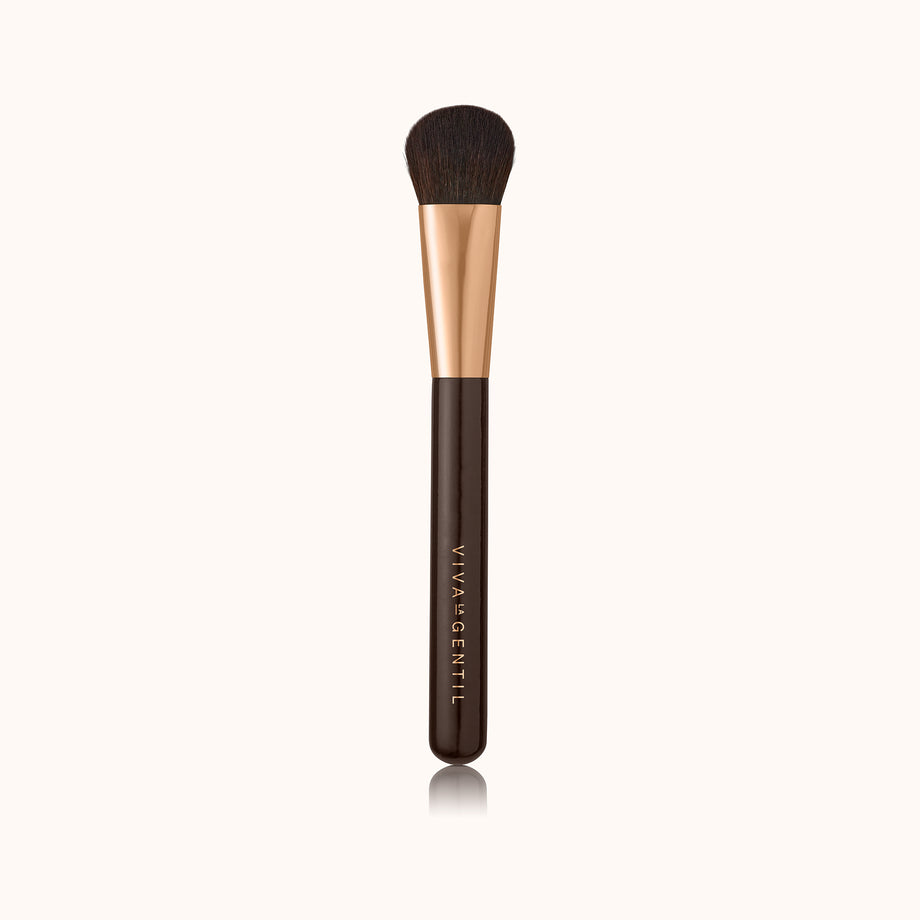 A medium sized domed shaped makeup brush with a dark brown lacquered handle and a rose gold ferrule, made by mixing handmade synthetic dark brown bristles with a few strands of white bristles.